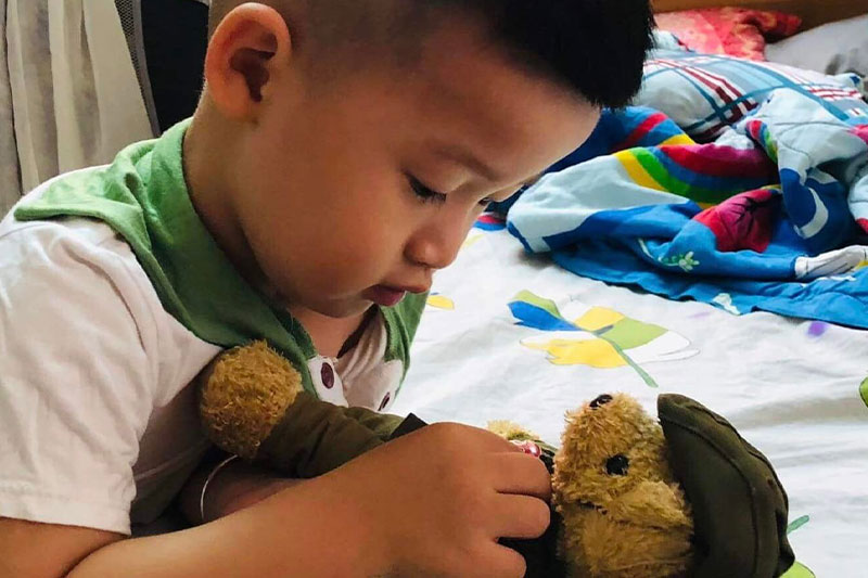 A young Vietnamese boy plays with an ANZAC Bear