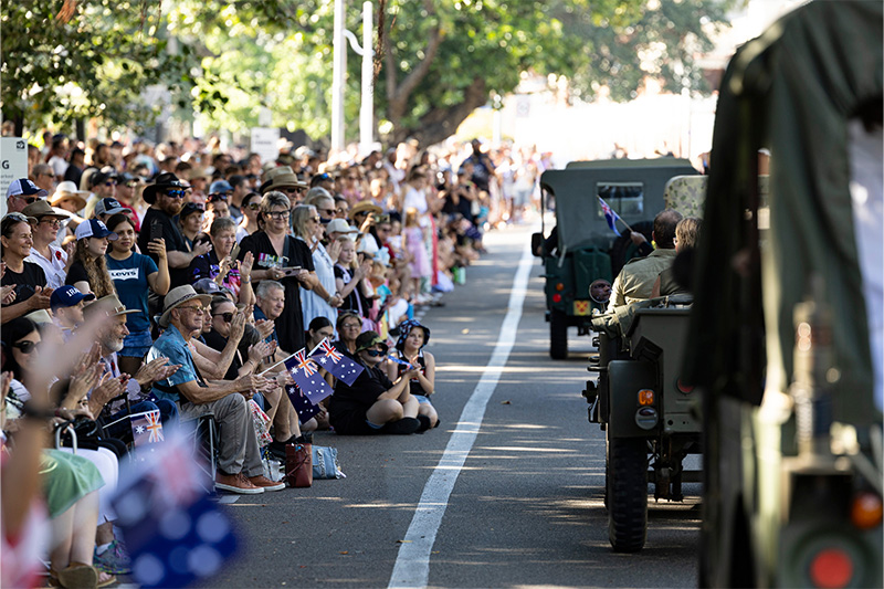 Members of the community wave to veterans as they march past during an ANZAC Day parade in Townsville, Queensland. Image credit: Department of Defence 