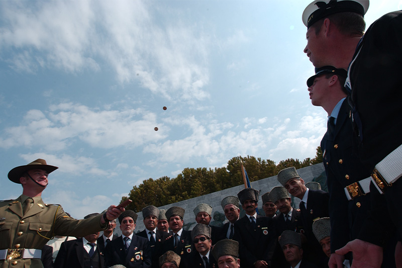 Image: Defence Australia |  Lance Bombardier Greg Meller, Leading Aircraftman Jonathon O'Brien and Leading Seaman Jeffery Streeter play two-up with Turkish veterans
