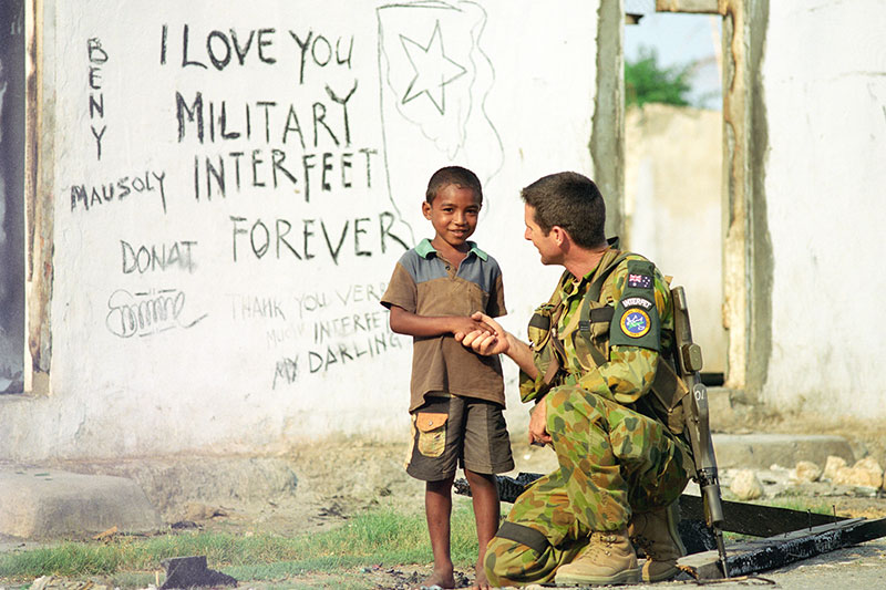Image: Defence Australia | Sergeant Martin Ryan shakes hands with an East Timorese child