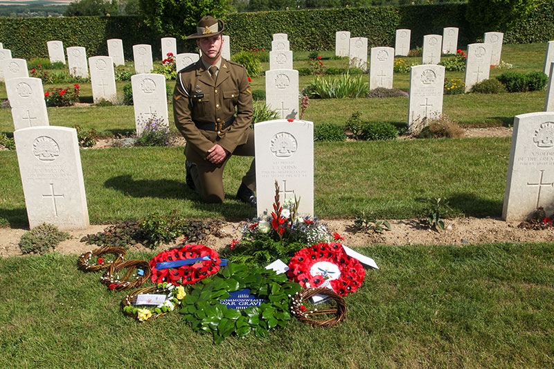 Image: Defence Australia | Lance Bombardier Jack Randell kneels at the headstone of PTE Quinn at Villers-Bretonneux Military Cemetery, France.
