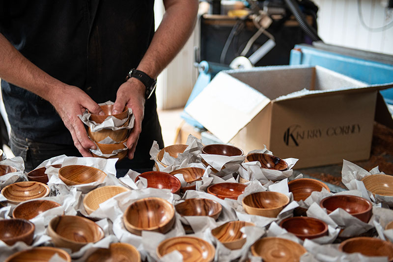 Army veteran Kerry Corney placing his handmade wooden bowls on a table. 