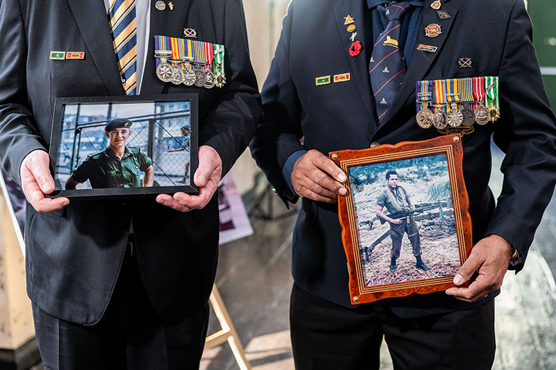 Vietnam veterans John Burns and Des Kearton holding framed photos of themselves taken during the Vietnam war. 
